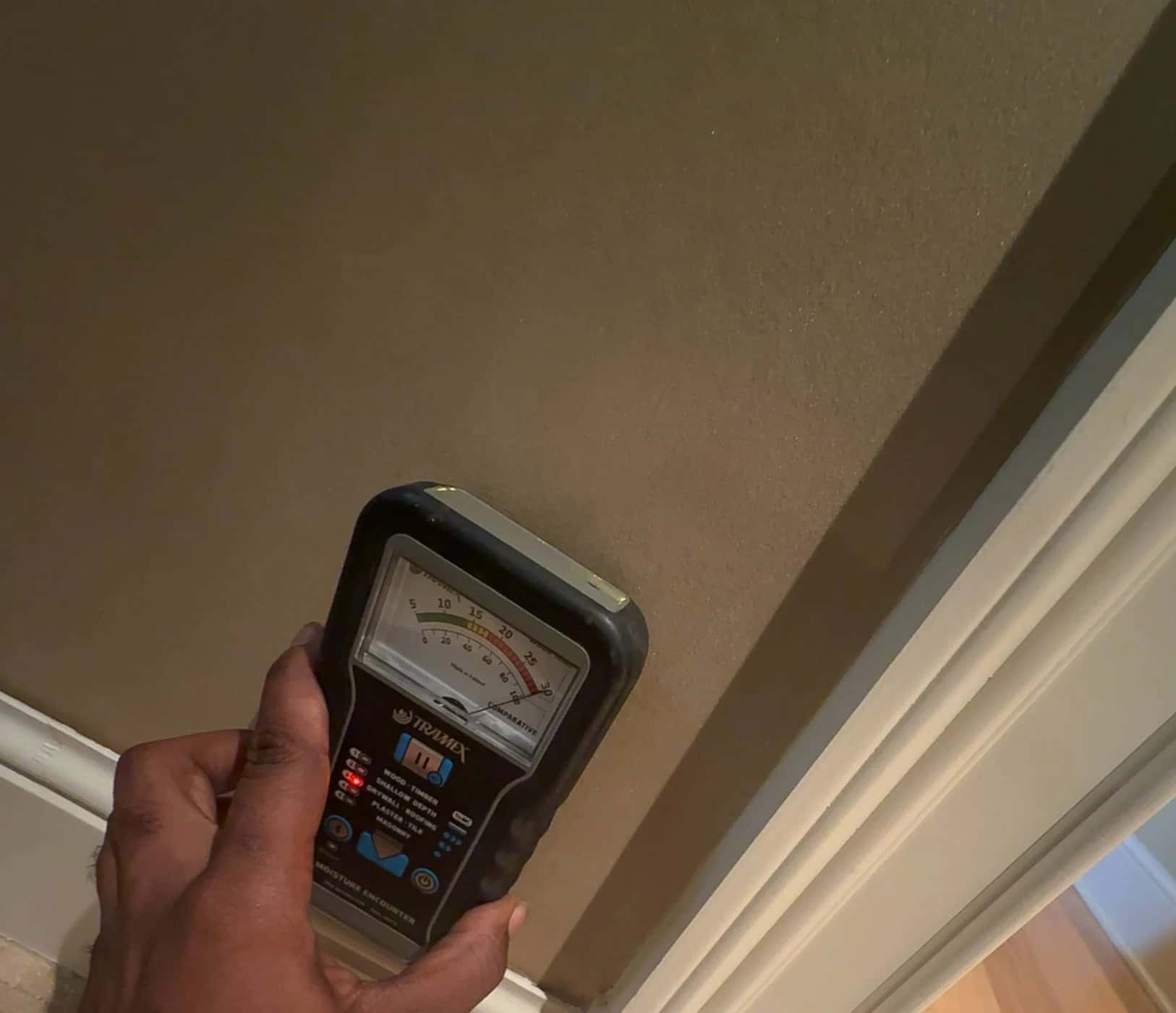 Moisture meter held against a wall during inspection.