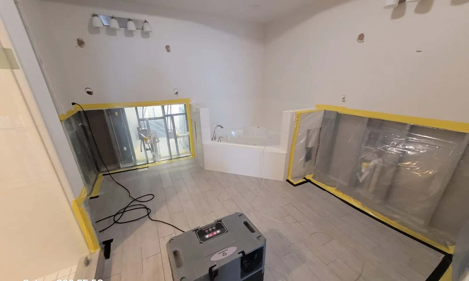 Bathroom with flood cuts, plastic containment, and drying equipment.